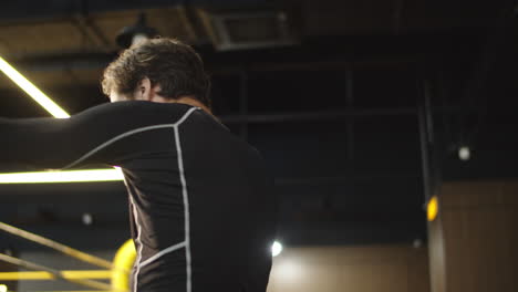 Strict-sport-man-warming-up-elbows-in-fitness-center.-Boxer-exercising-at-gym