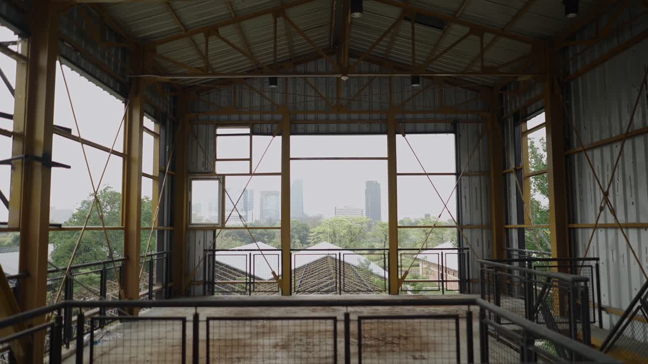 Industrial metal structure with a panoramic view of a city skyline and trees