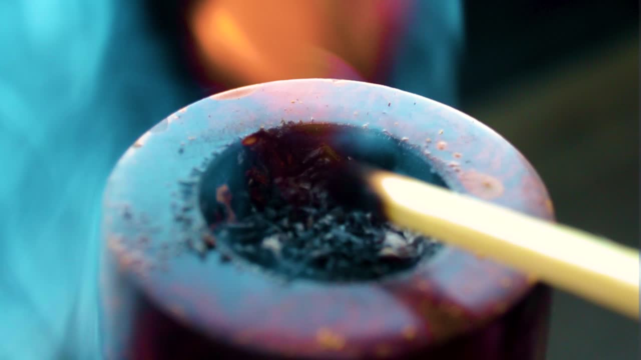 close-up of a match being lit against a wooden modern colourful pipe burned from the flames tobacco set on fire burning inside smoker puffing quality leaf's clouds of smoke around the item indoor