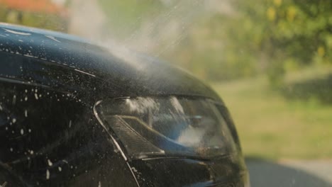 Pressurized-water-stream-rinsing-the-front-hood-of-an-auto-car