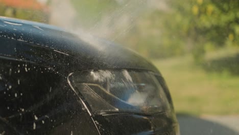 corriente de agua a presión que enjuaga el capó delantero de un automóvil
