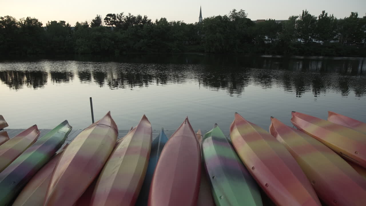 En tiltpanorering av en stabel med kajakker ved siden av Charles River i Waltham, MA.