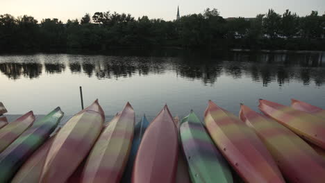 A-tilt-pan-of-a-stack-of-kayaks-next-to-the-Charles-River-in-Waltham,-MA