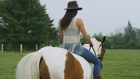 confident female horse rider riding a horse bareback through a field