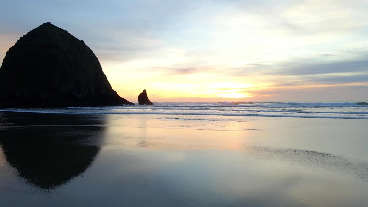Odraz barev západu slunce na písku na pláži Canon Beach v Oregonu