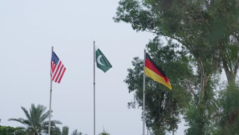 usa, pakistan and germany flags flying at full mast in unity and pride on a flag pole.