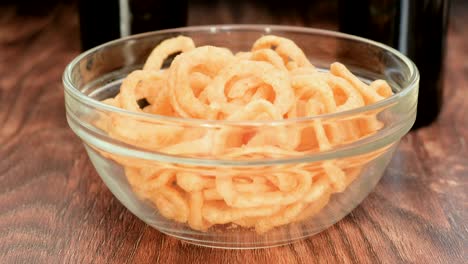 salty onion rings chips falling in glass transparent bowl.