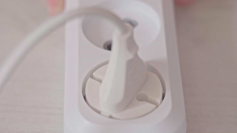 los enchufes de mano masculinos en el enchufe en el cable de extensión eléctrica del enchufe y enciende el interruptor de alimentación. insertando el enchufado en el encuentro