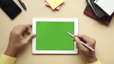 person using a tablet with a green screen