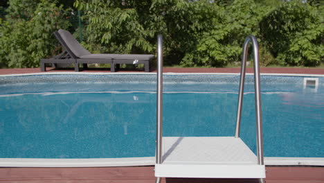 a swimming pool with a ladder and lounge chairs