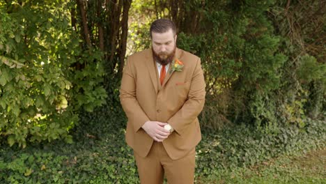 groom adjusts his watch and looks up and camera