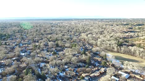 peaceful aerial footage of santa fe, new mexico in winter, showing patches of snow, warm light flare, and patrick smith park
