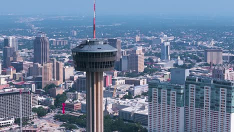 the hemisfair tower, also known as the tower of americas, sits in the heart of downtown san antonio texas surrounded by tall buildings, crowded highways and bustling city life