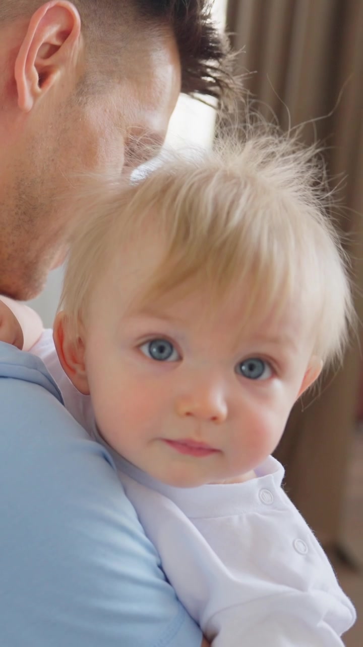 Primo piano di un bambino biondo e carino con gli occhi azzurri in braccio al padre