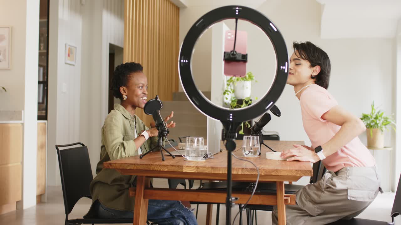Diverse coworkers placing headphones, adjusting light and preparing podcast with mics at home