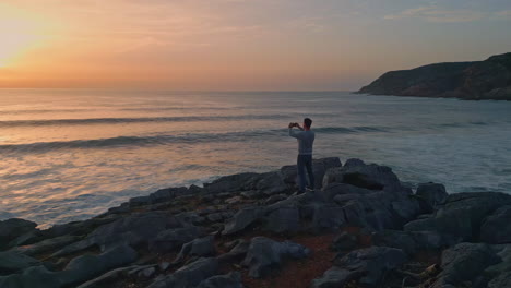 tourist man taking picture sunset ocean. marine sea waves reflecting bright sun