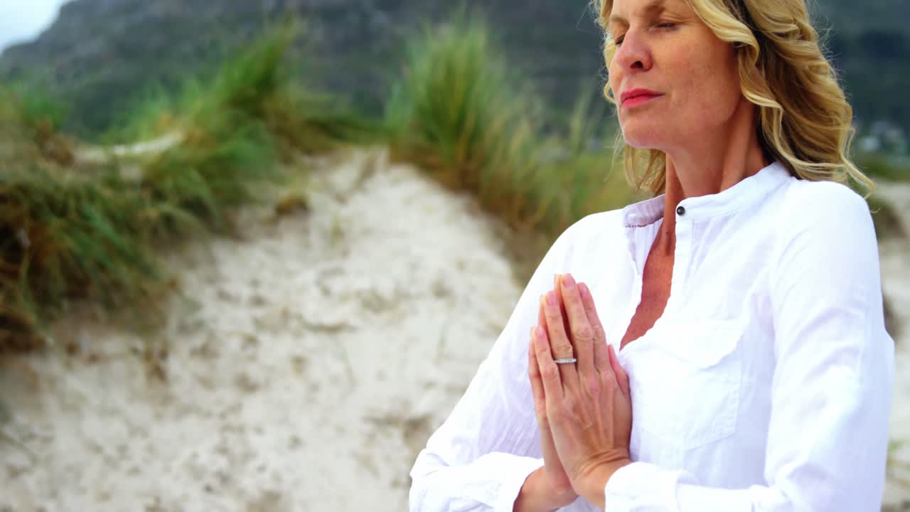 mujer madura haciendo yoga en la playa