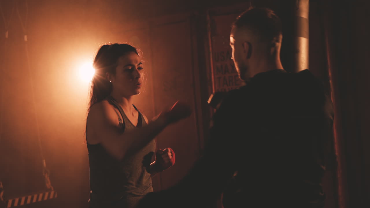 여자 복서가 트레이너의 장갑을 끼고 스트라이크를 피하다 1