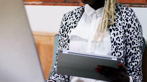 Female-executive-working-on-personal-computer-while-holding-digital-tablet