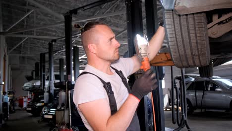 a mechanic inspects a car's wheel area in an auto repair shop