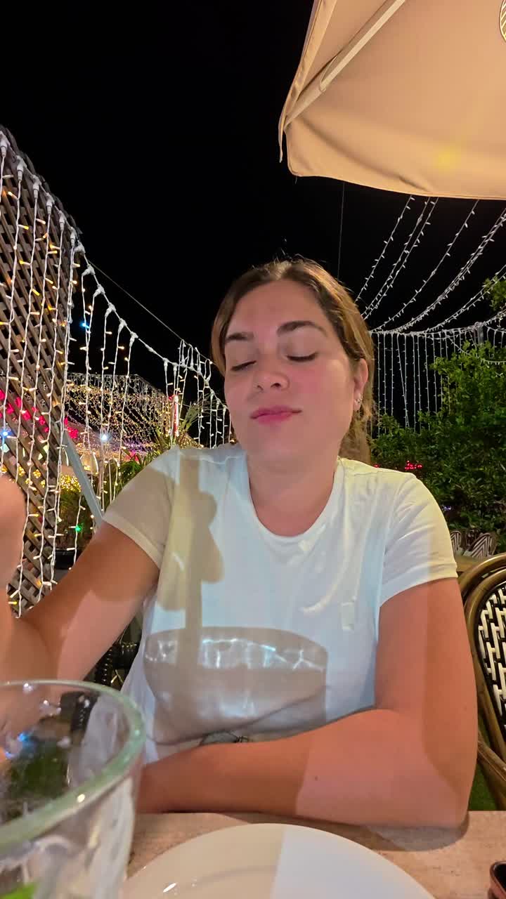 Kvinde, der bruger sin telefon på en restaurant med en mojito