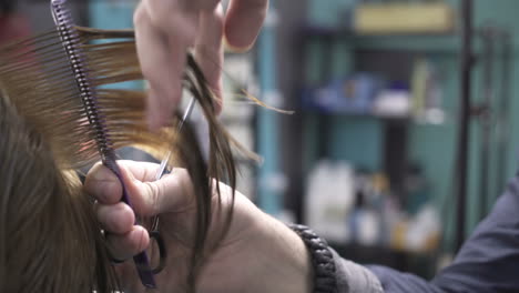 young woman with hairdresser cutting hair at salon