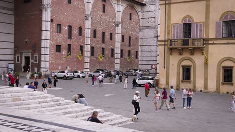 stabilized shot of people walking on a street surrounded by old buildings in tuscany, italy, on a cloudy day. slow motion.