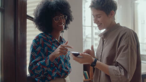 female colleagues using phone and chatting in the office