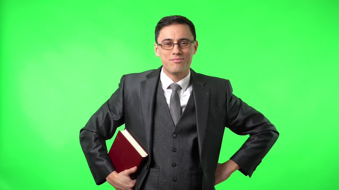 Man in a suit holding a book on a green screen