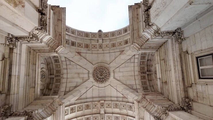 Ripresa a piedi sotto l'iconico Arco di Rua Augusta a Lisbona, Portogallo, che mostra una grandiosa architettura storica e un'atmosfera cittadina vivace.