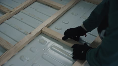 person constructing base for floor structure in white van, close up