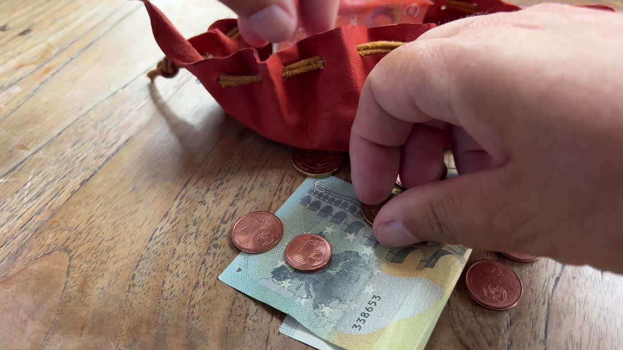 손으로 만든 작은 가죽 가방에 돈을 넣고 그것을 닫고, 유로 동전과 지폐를 닫습니다.