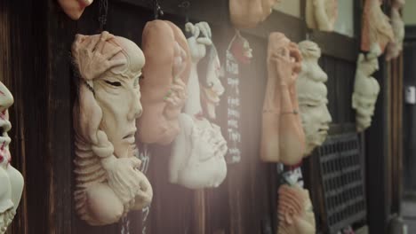 Slide-shot-of-Japanese-masks-decorated-on-a-wall-in-Kyoto,-Japan-4K-slow-motion