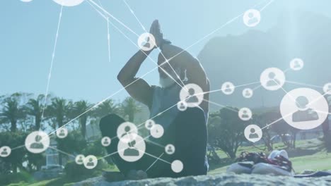 Animation-of-network-of-connections-over-senior-african-american-man-practicing-yoga-at-beach