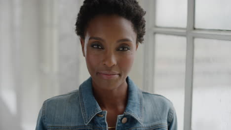 close up portrait of independent african american woman looking serious at camera relaxed black female wearing denim jacket in apartment windows background
