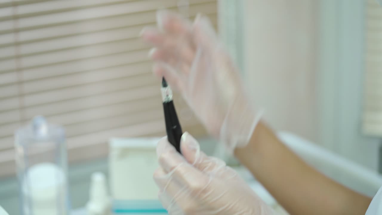 beautician is showing a brush with a needle at the end in her hands for permanent makeup. Modern methods of cosmetology.