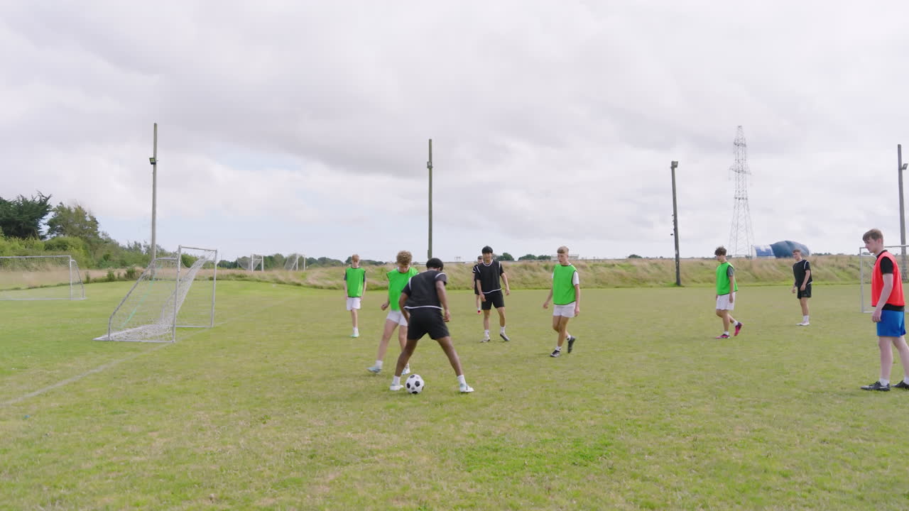 Multiracial male soccer players playing soccer, running after and passing ball on pitch