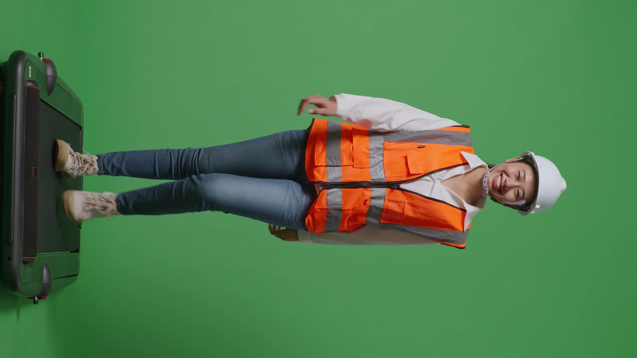 cuerpo lleno de ingeniera asiática con casco de seguridad y caminando en el estudio de fondo de pantalla verde