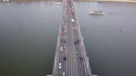 aerial view of traffic at bridge above river danube during sunset at budapest with the city in the background