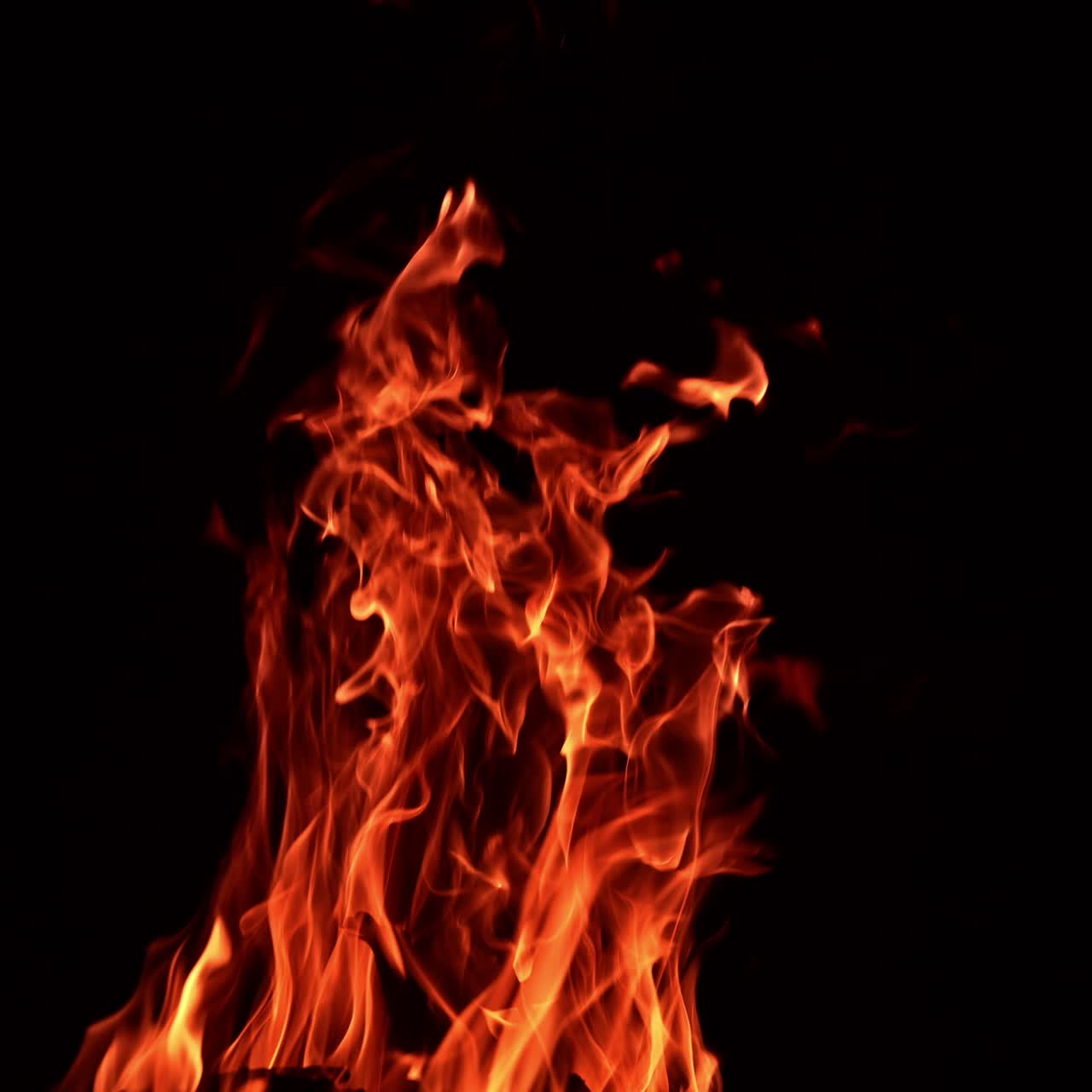 Pieces of wood burning in a big campfire. Large tongues of flame rising up in the darkness