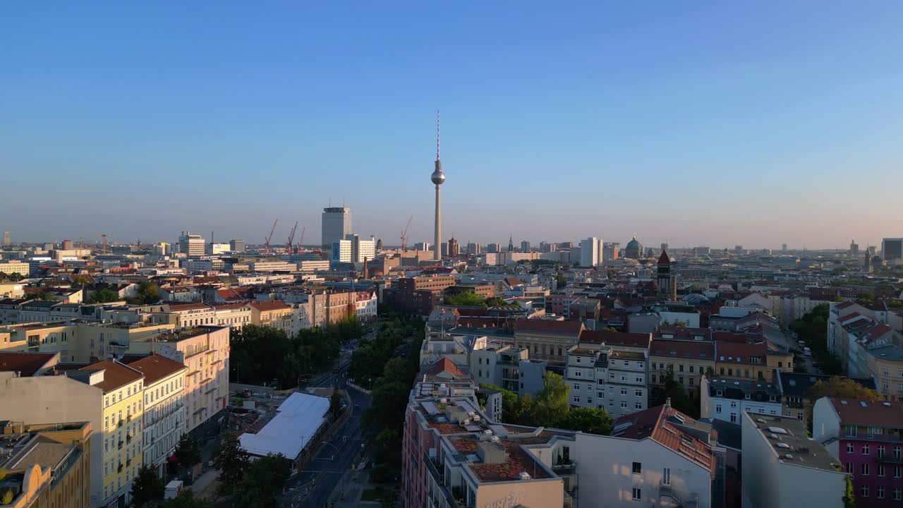 Berlin tv tower rising above rooftops and a construction site at senefelderplatz during sunset. Perfect aerial view flight overflight flyover drone