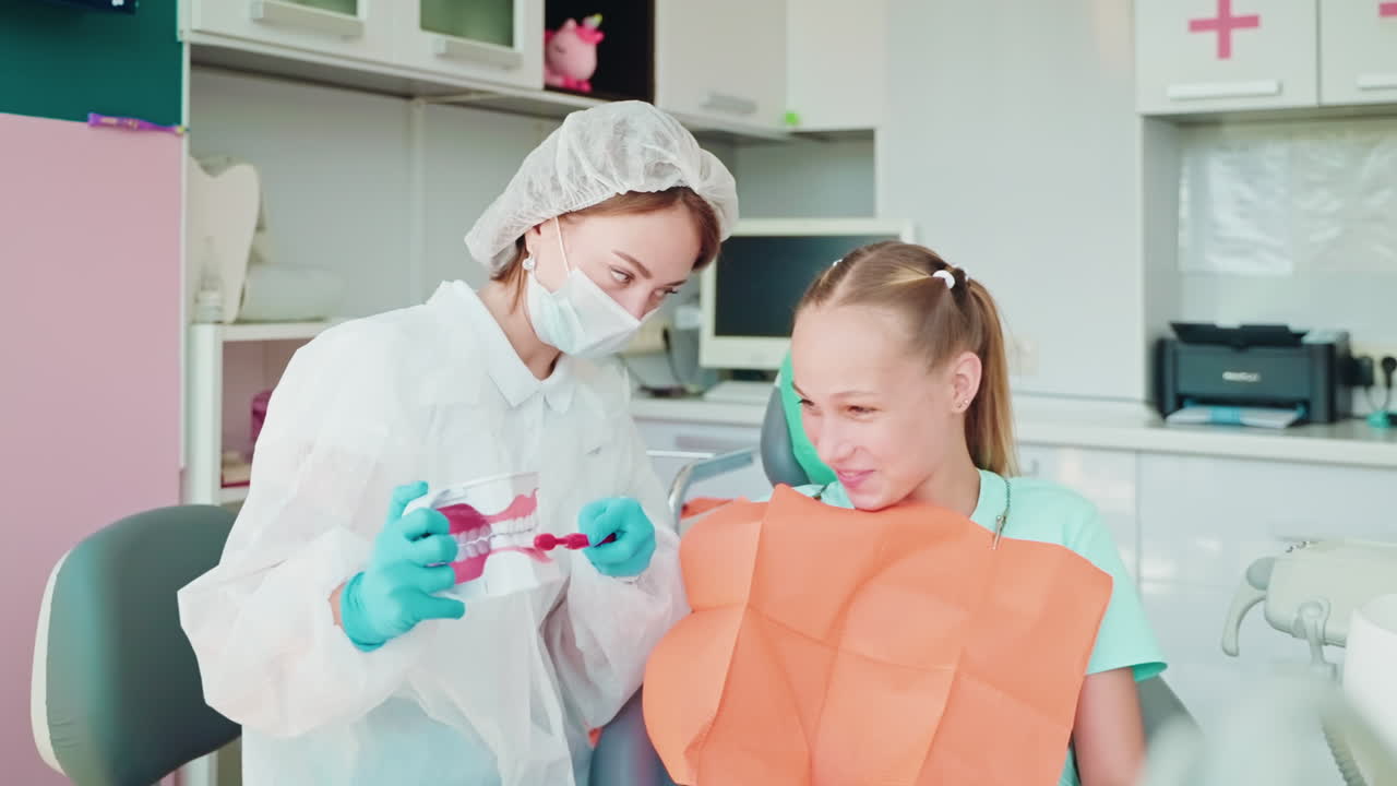 стоматолог учит девушку гигиене зубов