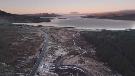 Kurvenreiche-Straße-Auf-Der-Insel-Skye-Mit-Seen-Und-Hügeln-In-Der-Dämmerung,-Luftaufnahme