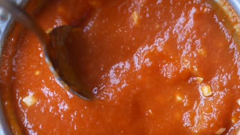 close up of tomato sauce being stirred in a pot