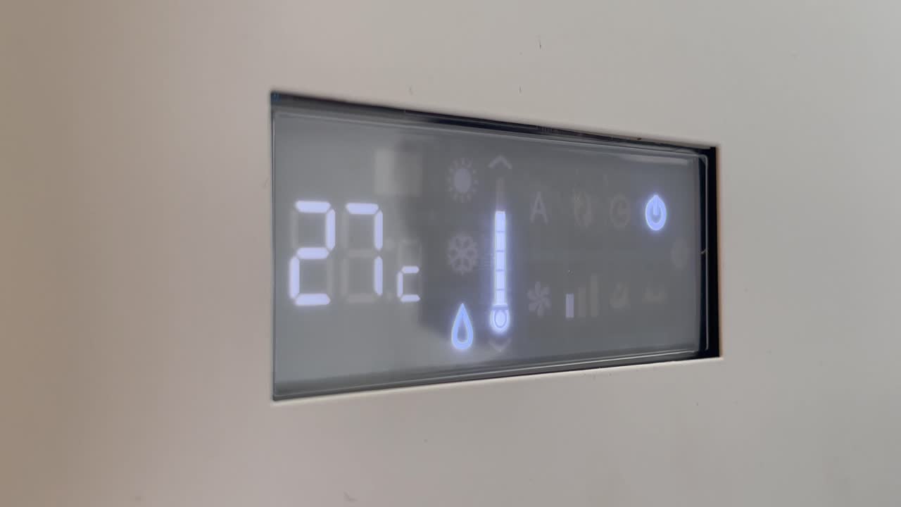 Digital air conditioner screen turning on and cooling set to 23 degrees Celsius. Concept of summer heat relief and indoor comfort.
