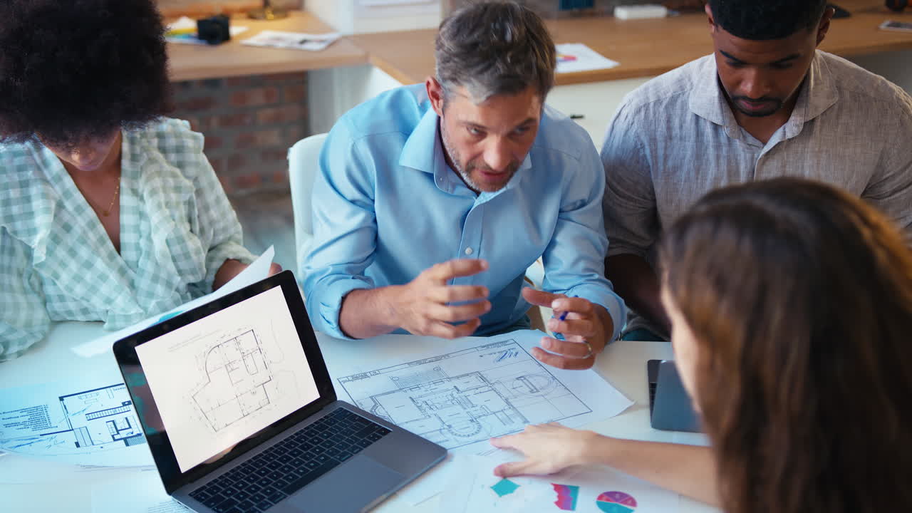 vista elevada del equipo de negocios masculino y femenino con reunión de computadora portátil en una oficina moderna