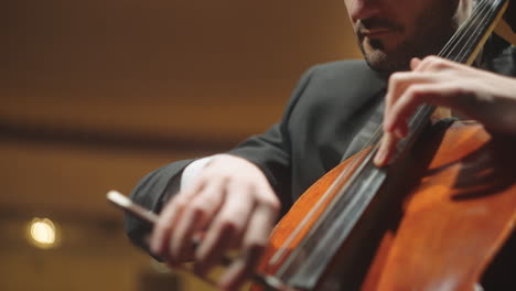 professional cellist is playing violoncello in symphonic orchestra in philharmonic hall