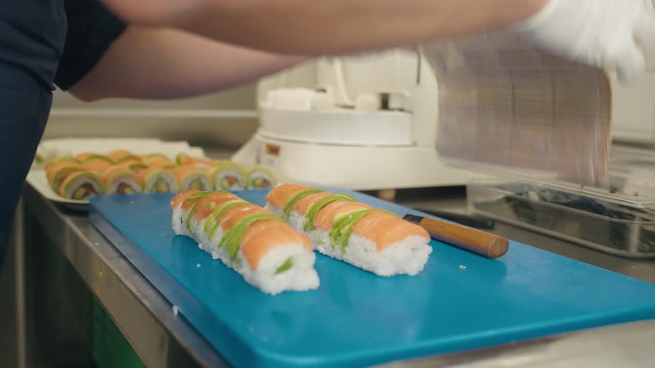 Henkilö asettaa lohta nigiri-sushin päälle, lähikuva.