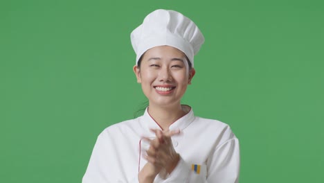 Close Up Of Asian Woman Chef Smiling And Clapping Her Hands While Standing In The Green Screen Background Studio