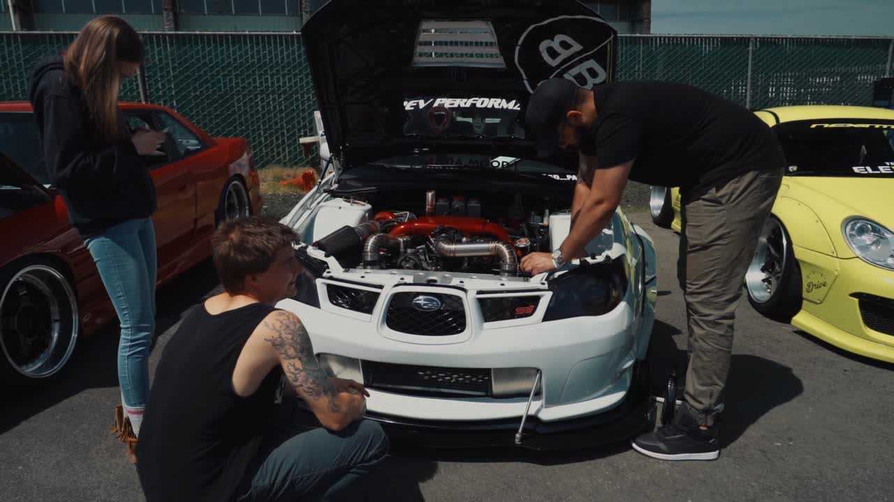 Car Show Spectators Inspecting a White Subaru STI.
